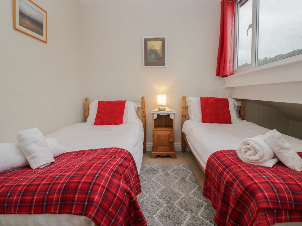 A bedroom with two beds, a lamp and artwork at Cloud Cottage in Ambleside