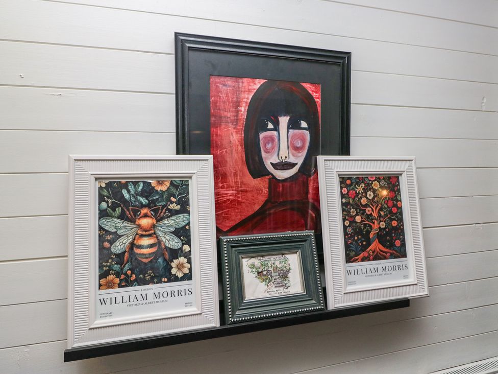 Artworks on a shelf including portraits and nature-themed prints at Moon Cottage White Cross Bay Holiday Park near Troutbeck Bridge