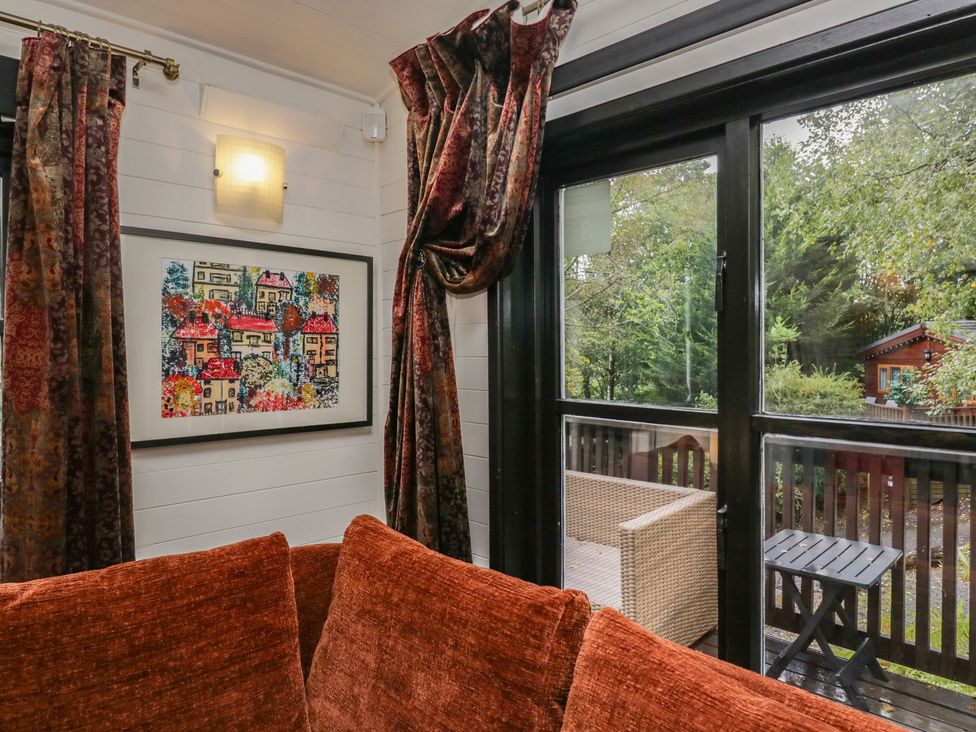 A living room with a window and couch at Moon Cottage near White Cross Bay Holiday Park near Troutbeck Bridge