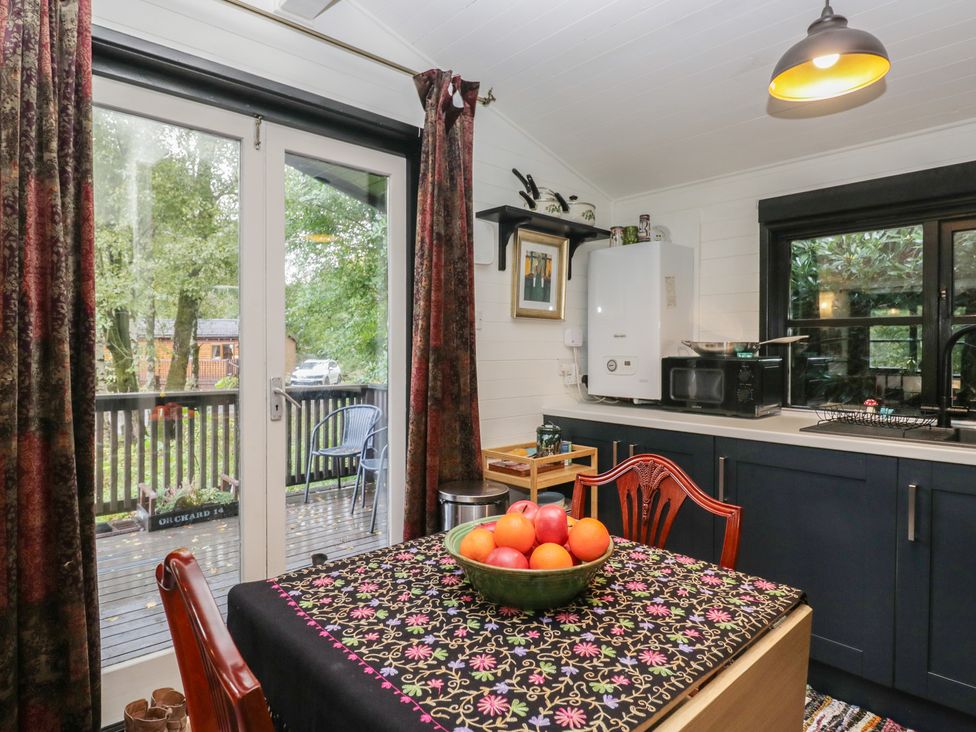 A kitchen with a table and fruit bowl at Moon Cottage in White Cross Bay Holiday Park near Troutbeck Bridge