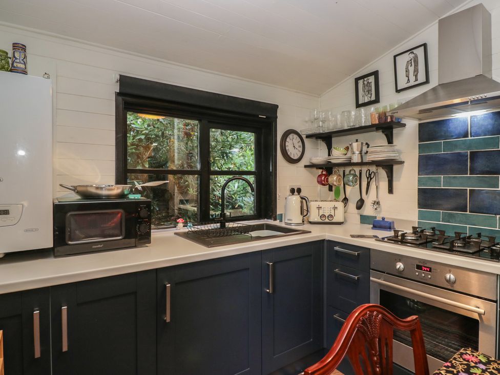 A kitchen with appliances and a window at Moon Cottage in White Cross Bay Holiday Park near Troutbeck Bridge