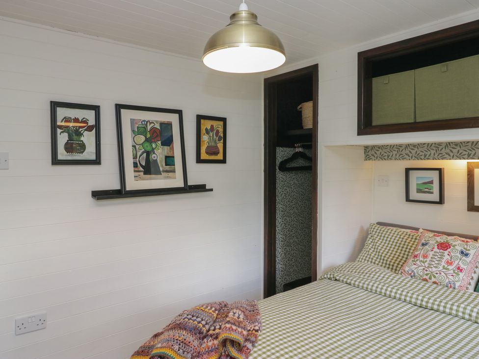 A bedroom with a bed and artwork on the wall at Moon Cottage White Cross Bay Holiday Park near Troutbeck Bridge