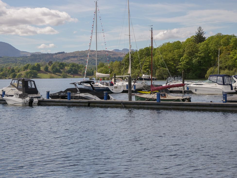 Boats docked at a marina with mountains in the background at Moon Cottage White Cross Bay Holiday Park near Troutbeck Bridge