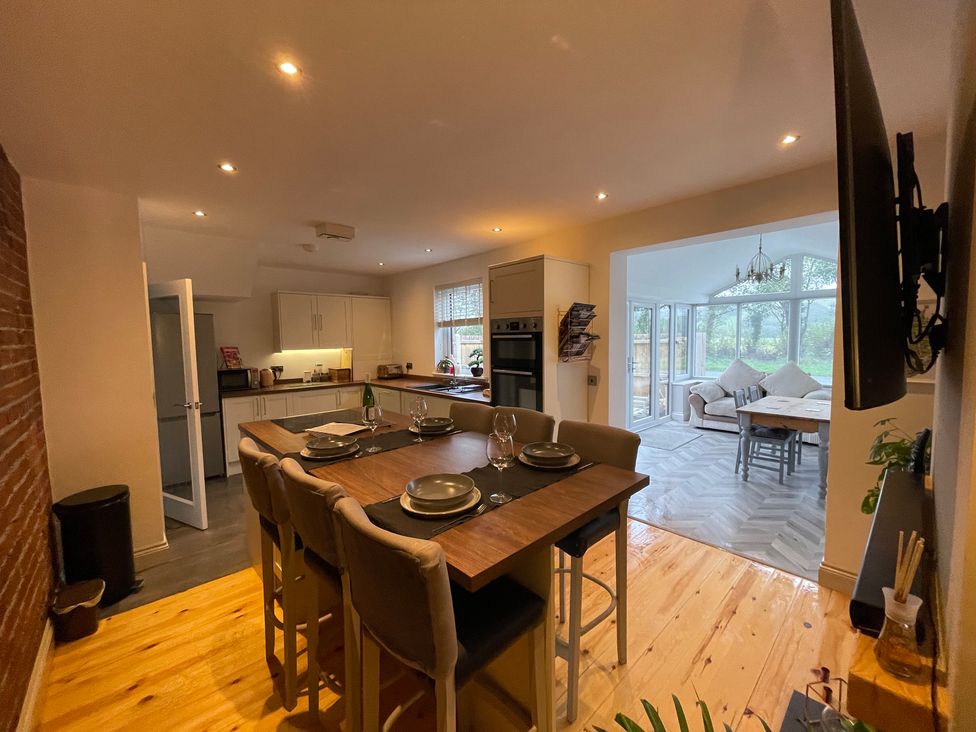 A kitchen with a dining table and bar stools at Dolwen, Caernarfon
