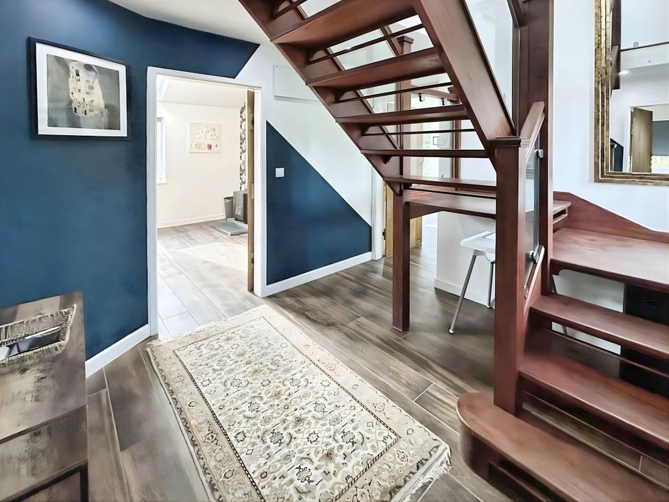 A hallway with a staircase and a rug at Hen Stablau, Corwen
