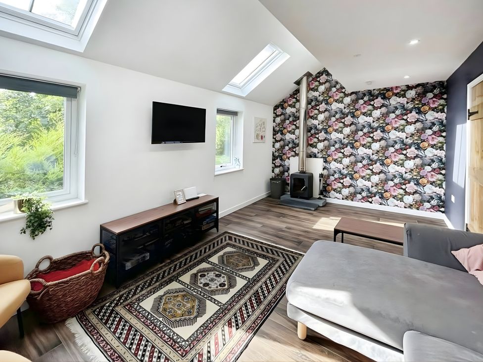 A living room with a sofa and television at Hen Stablau in Corwen