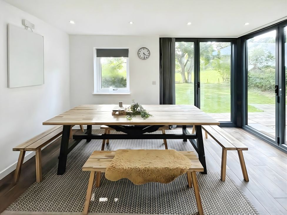 A dining room with a large table and benches at Hen Stablau in Corwen