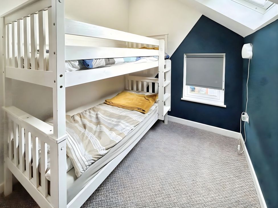 A bedroom with a bunk bed and a window at Hen Stablau in Corwen