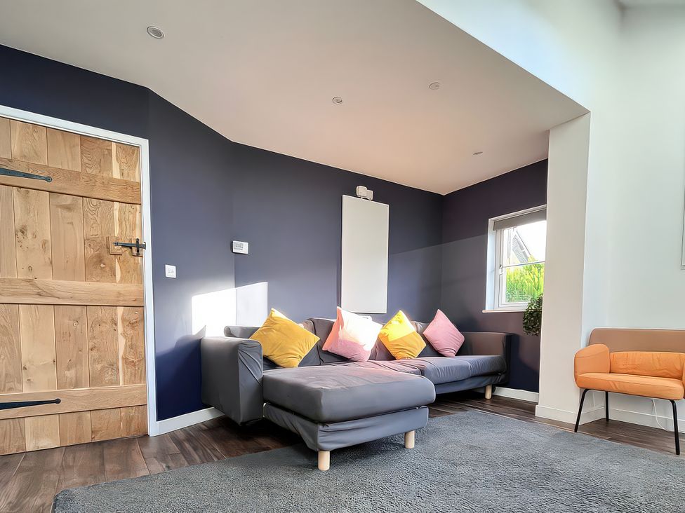 A living room with a sofa and a door at Hen Stablau Dinmael near Cerrigydrudion