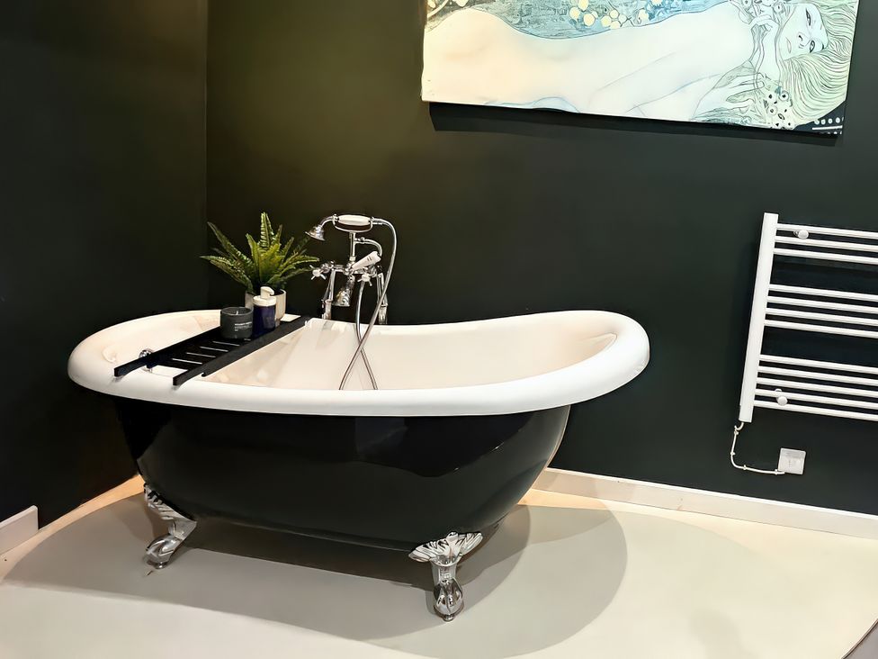 A bathtub with a plant and tray in a bathroom at Hen Stablau Dinmael near Cerrigydrudion