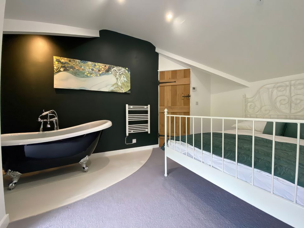 A bedroom with a bed and bathtub at Hen Stablau Dinmael near Cerrigydrudion