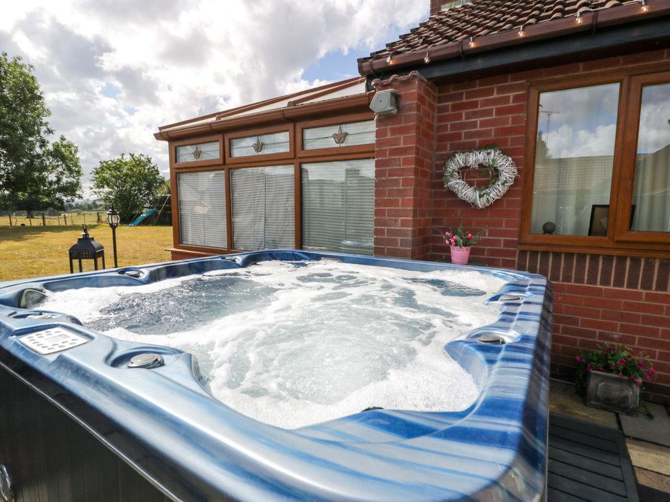 A hot tub outside with a brick wall and window at Pentre Country Studio near Chirk