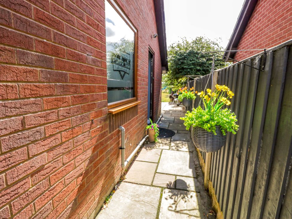 An outdoor pathway with flowers and brick walls at Pentre Country Studio near Chirk