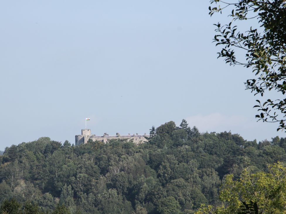 A castle on a hill with trees in the foreground at Pentre Country Studio near Chirk