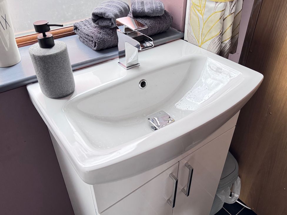 A sink with soap dispenser and towels at Pentre Country Studio near Chirk