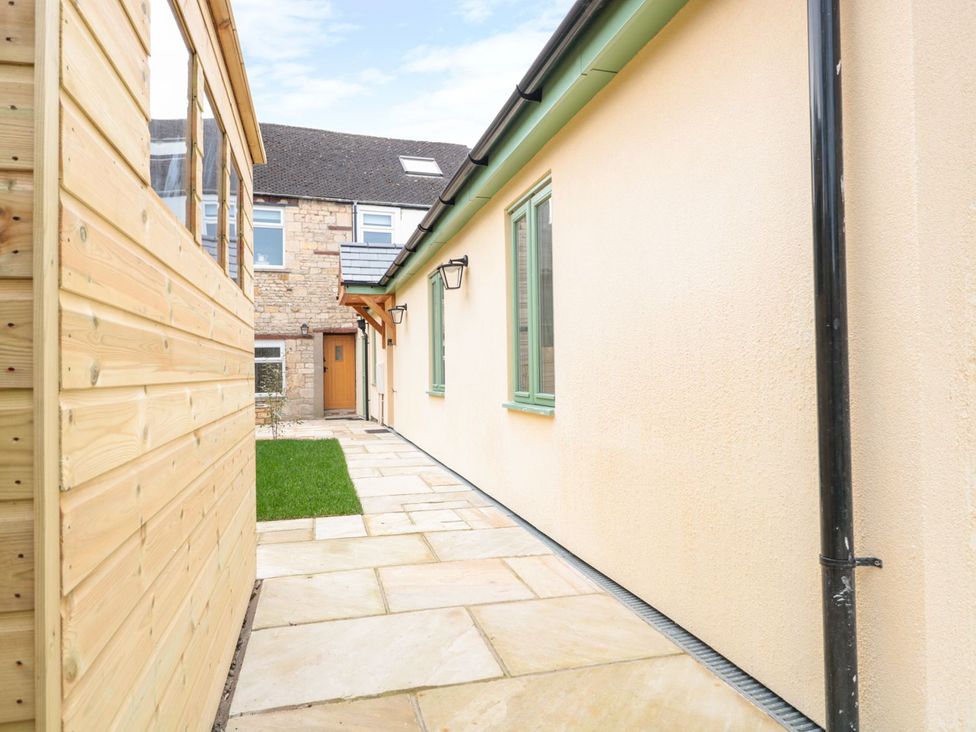 An outdoor pathway between a wooden shed and a stone wall at The Old Sorting Office