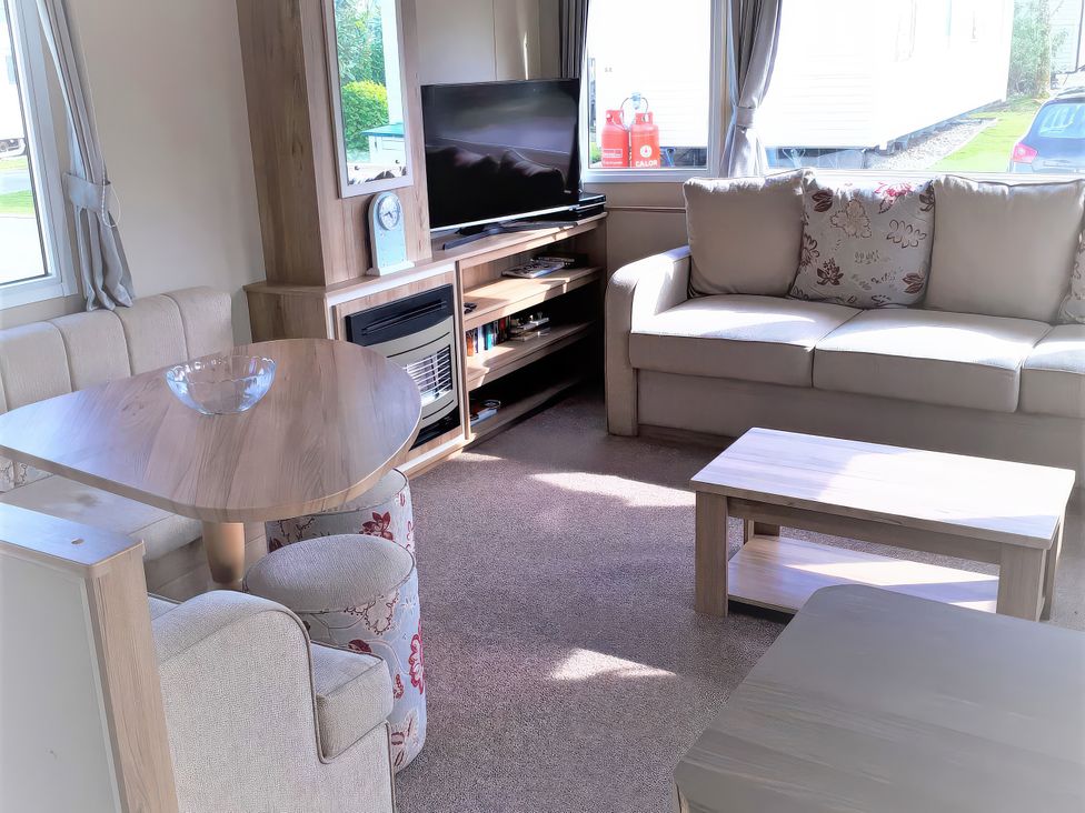 A living room with a sofa, coffee table, and television at Par Sands Holiday Park - 6388, Par