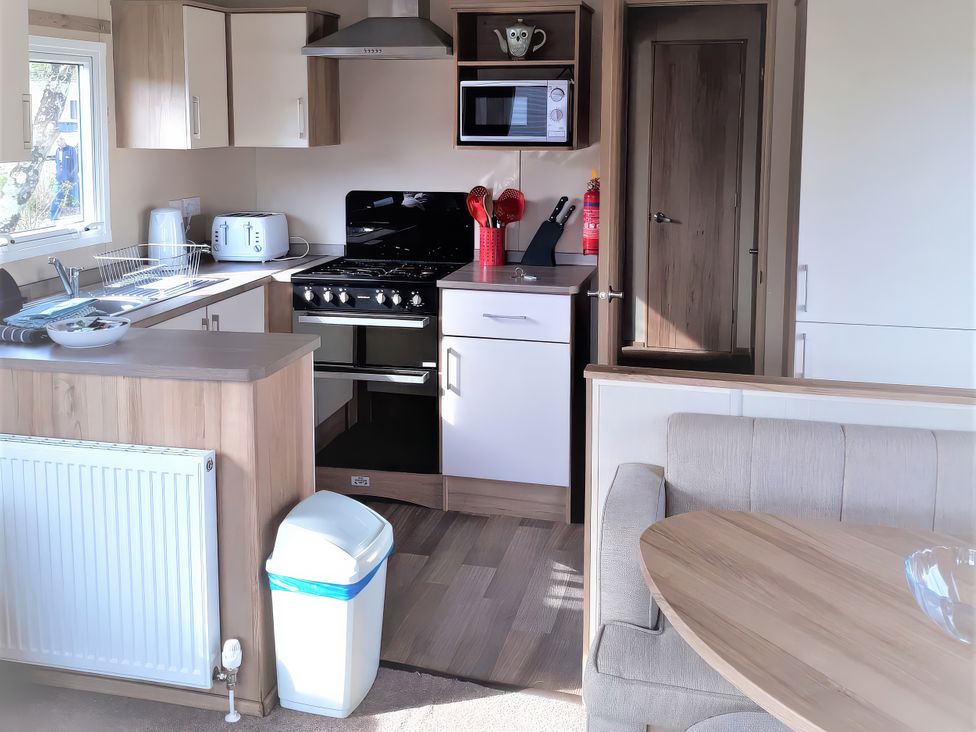 A kitchen with appliances and furniture at Par Sands Holiday Park - 6388 in Par