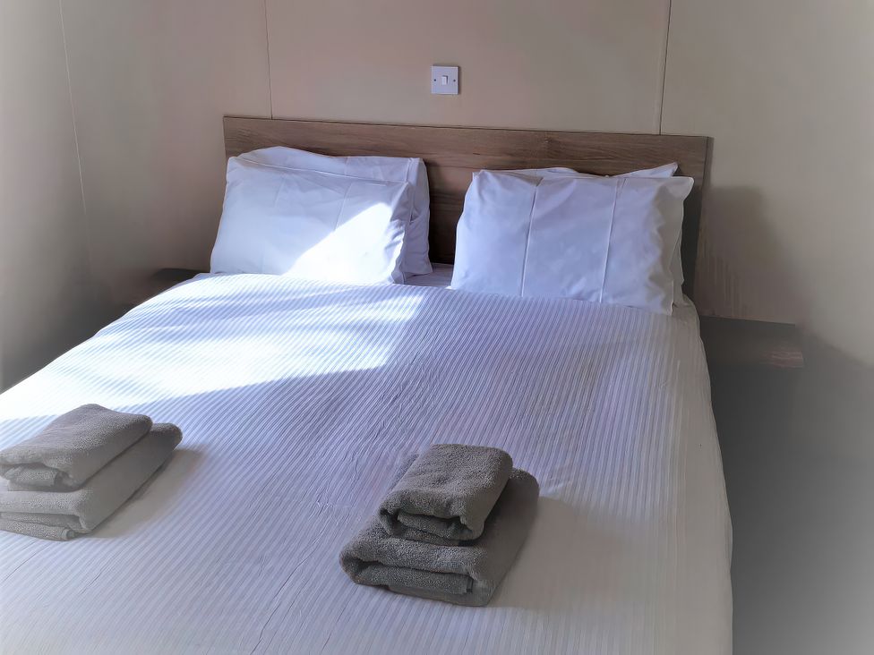 A bed with pillows and towels at Par Sands Holiday Park - Par