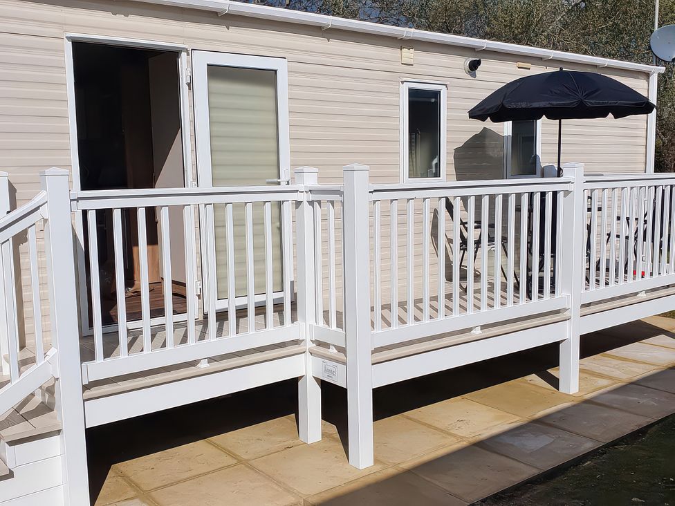 An outdoor deck with railing and an umbrella at Par Sands Holiday Park - 6388, Par