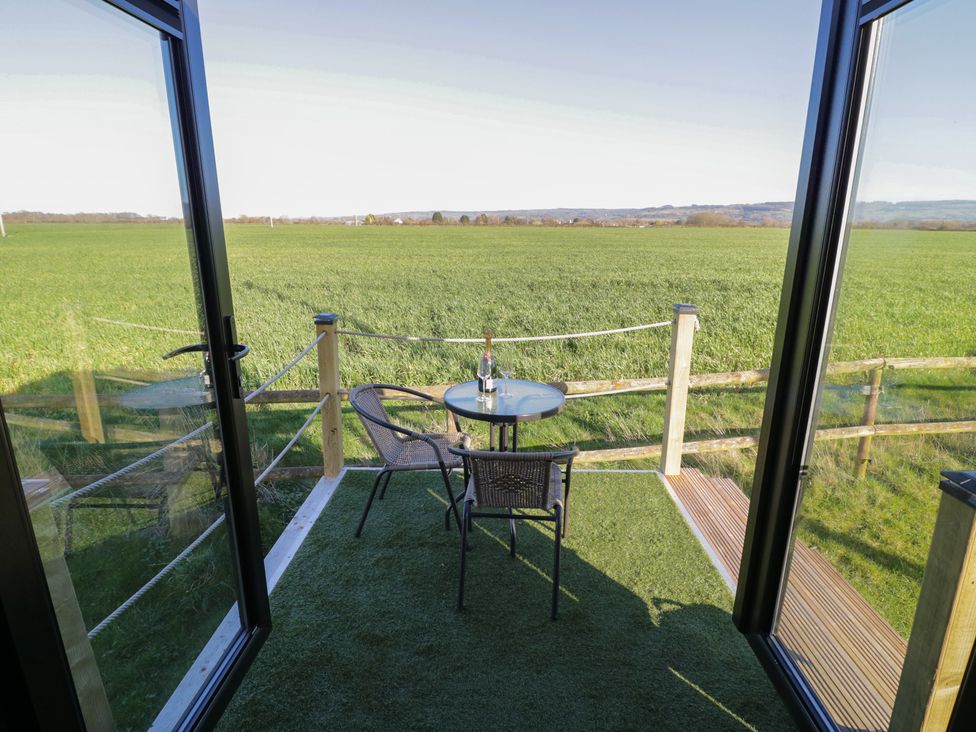An outdoor seating area with a table and chair overlooking a field at GiGi's Horsebox in Evesham