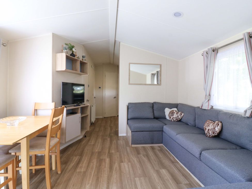 A living room with a sofa and dining area at Singh and Leite Family Caravan St. Osyth