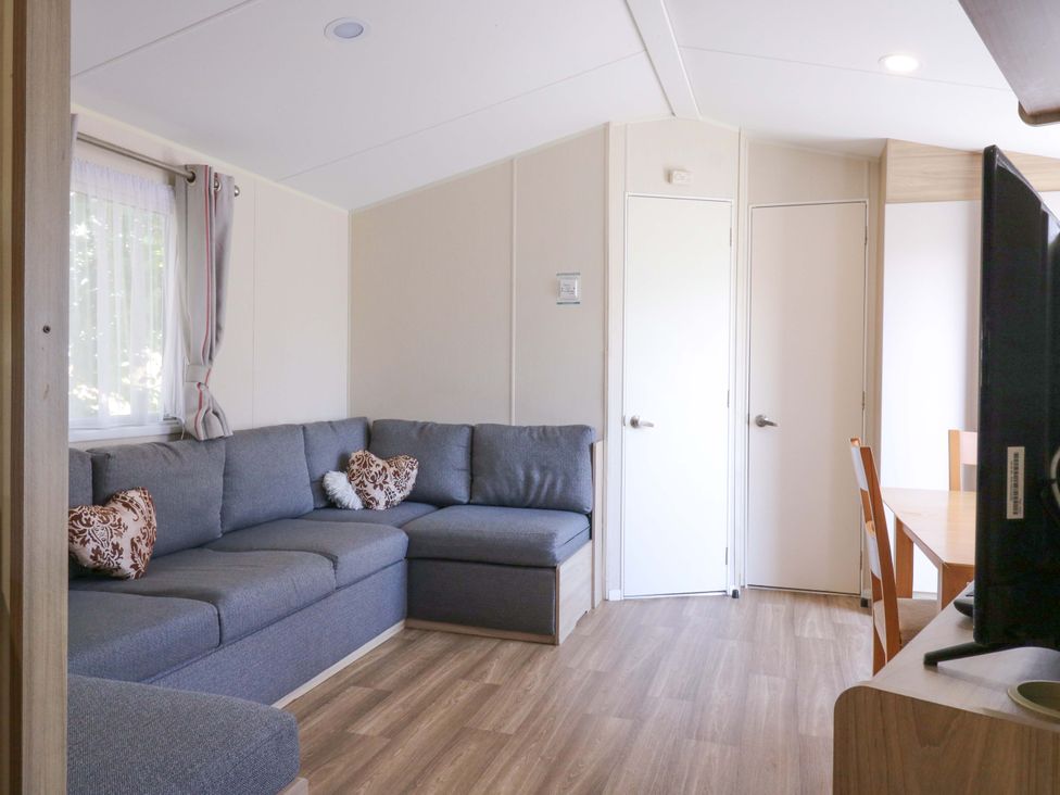 A living room with a sofa and dining table at Singh and Leite Family Caravan, St. Osyth