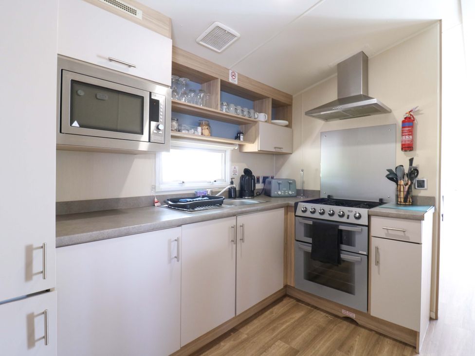 A kitchen with cabinets and appliances at Singh and Leite Family Caravan in St. Osyth