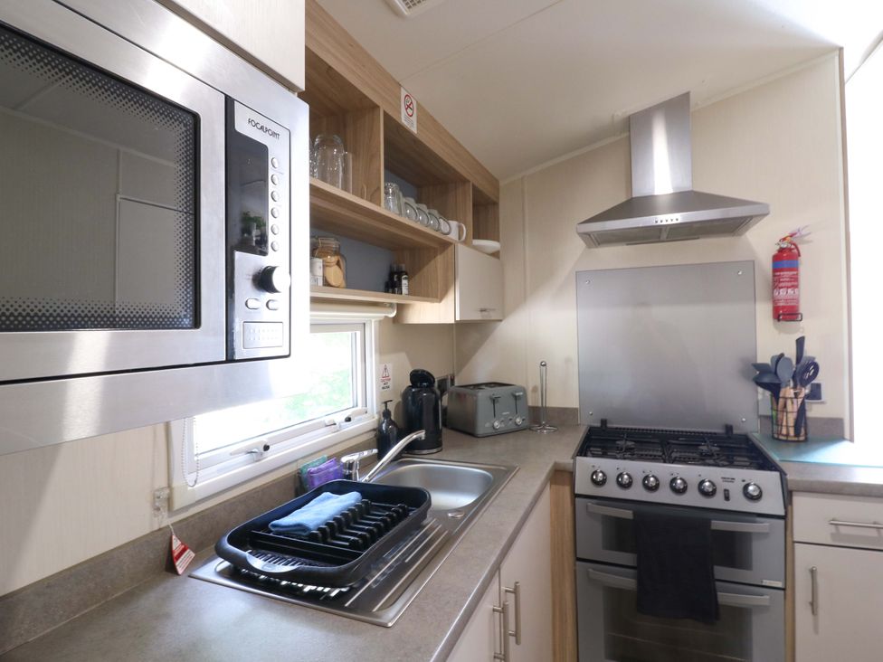 A kitchen with appliances including a microwave and a stove at Singh and Leite Family Caravan St. Osyth