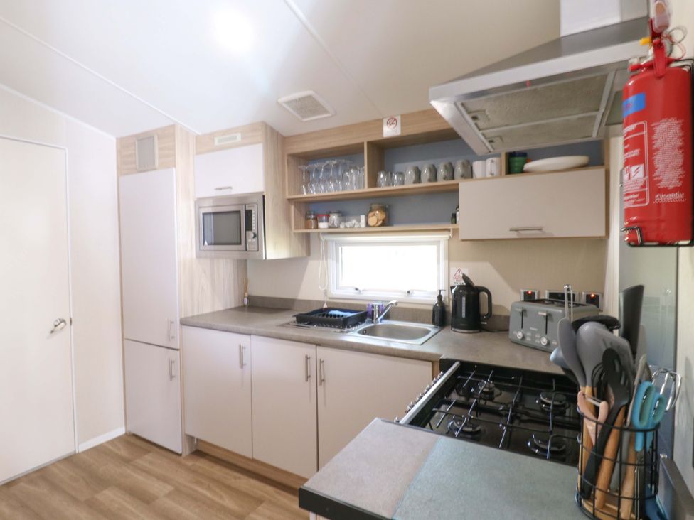 A kitchen with sink, stove, and microwave at Singh and Leite Family Caravan St. Osyth