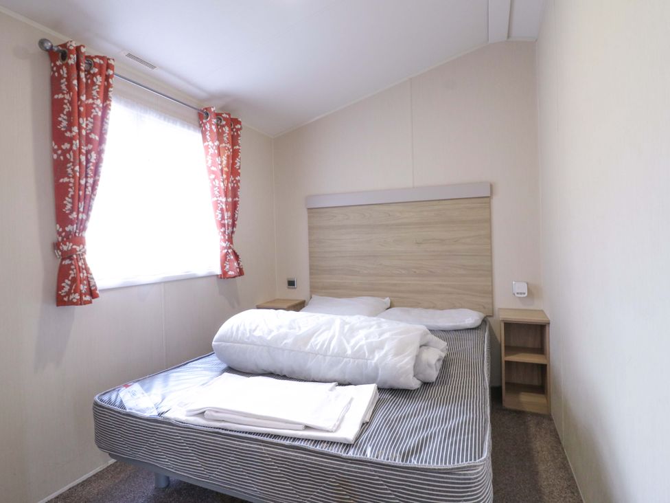 A bedroom with a bed and bedside table at Singh and Leite Family Caravan St. Osyth