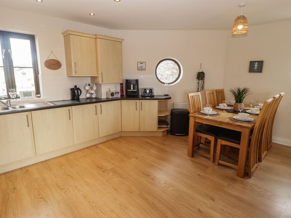A kitchen with a dining table and chairs at Awel y Môr in Burry Port