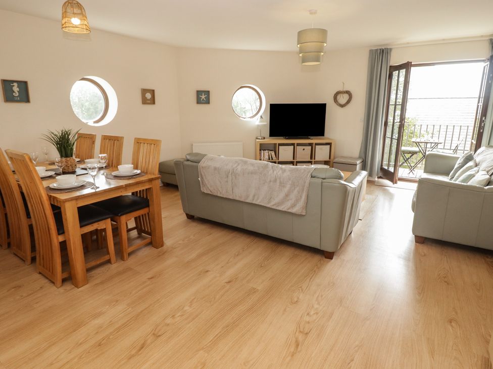 A living room with a dining table and chairs, sofa, and television at Awel y Môr, Burry Port