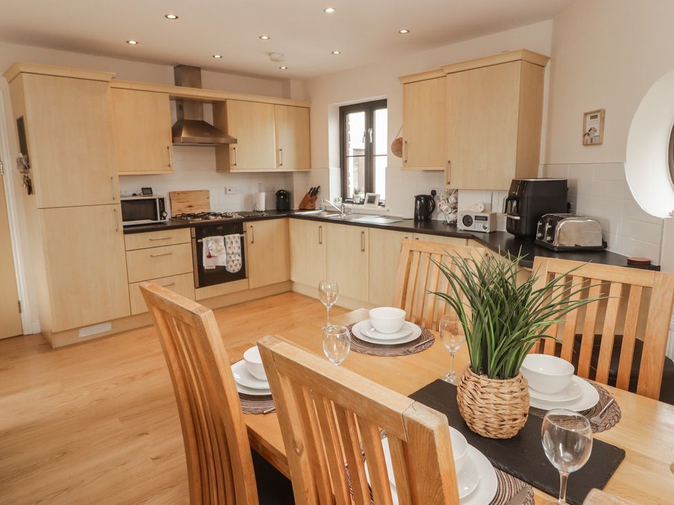 A kitchen with cabinets, stove, and dining table at Awel y Môr in Burry Port