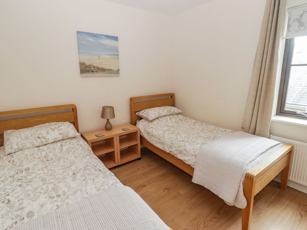 A bedroom with two single beds and a nightstand at Awel y Môr in Burry Port