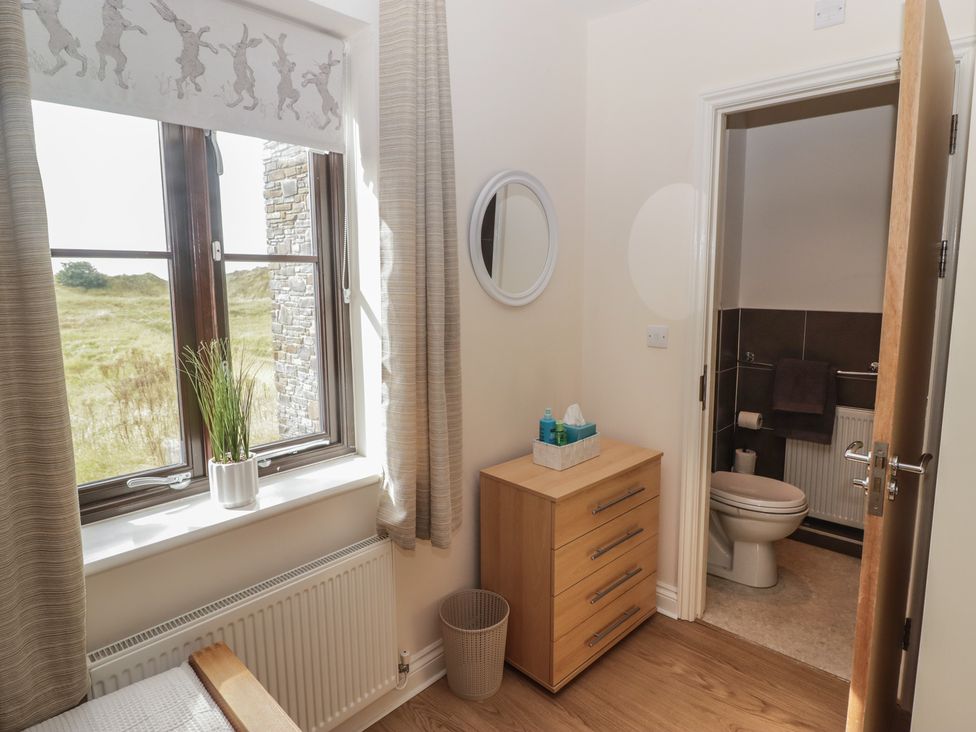A bedroom with a bathroom and furniture at Awel y Môr, Burry Port