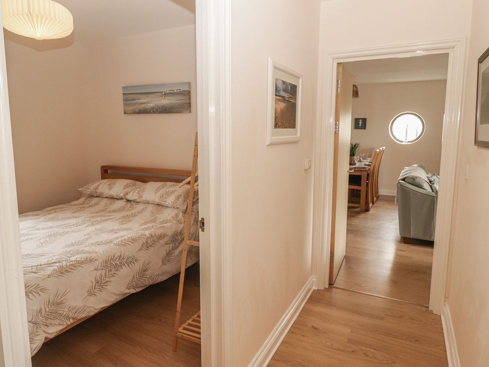 A bedroom with a bed and hallway leading to another room at Awel y Môr Burry Port