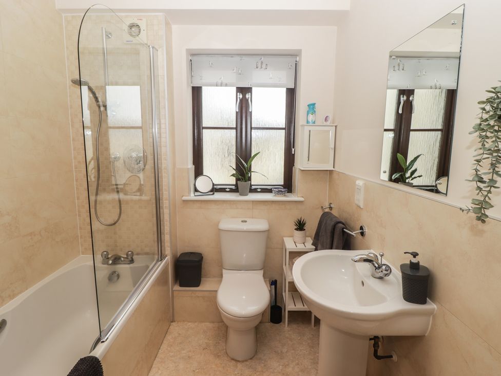 A bathroom with shower, bathtub, toilet, and sink at Awel y Môr Burry Port