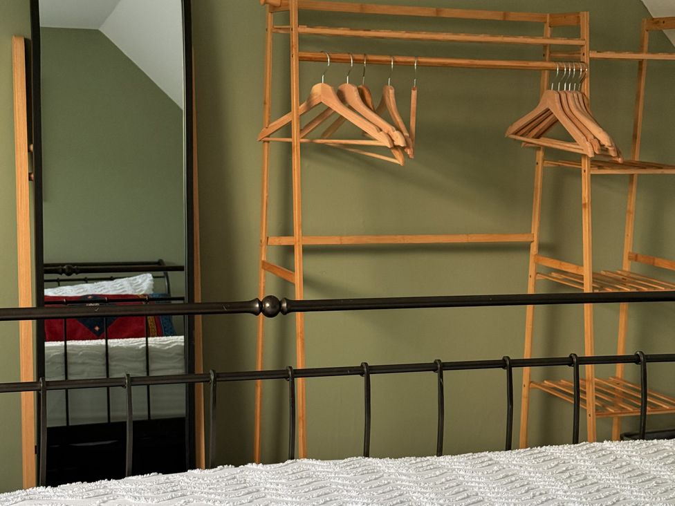 A bedroom with a mirror and a clothing rack at Portknockie Cottage in Buckie