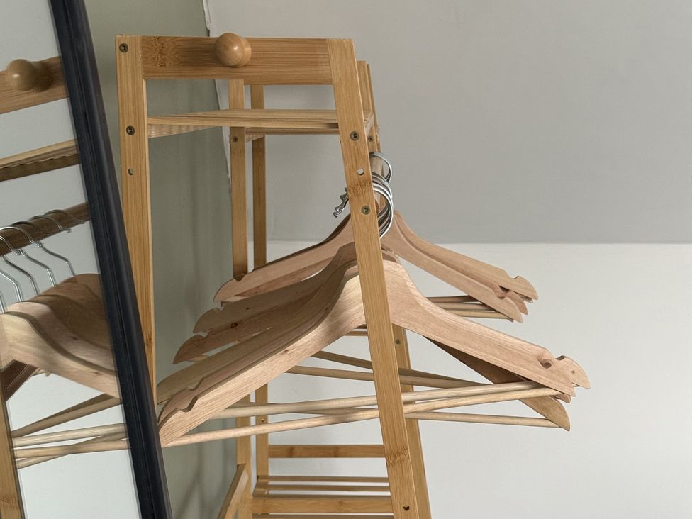 A clothing rack with wooden hangers and a mirror at Portknockie Cottage in Buckie