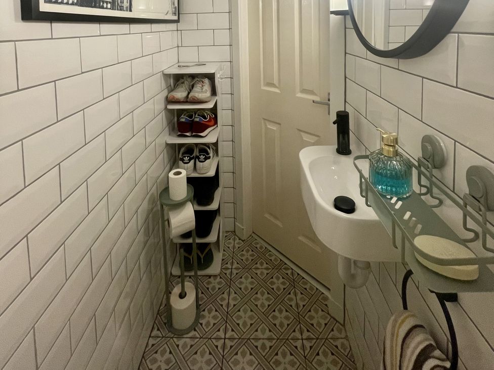 A bathroom with a sink and shelves for shoes at Portknockie Cottage in Buckie