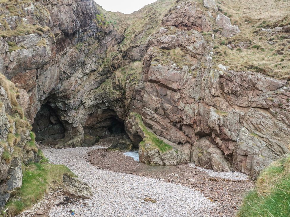 A rocky coastal area with pebbles and water at Portknockie Cottage in Portknockie