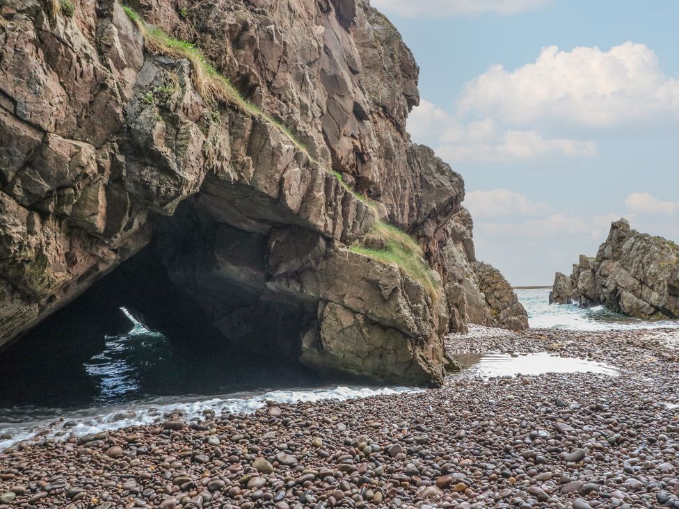 A beach with rock formations and a cave at Portknockie Cottage in Portknockie