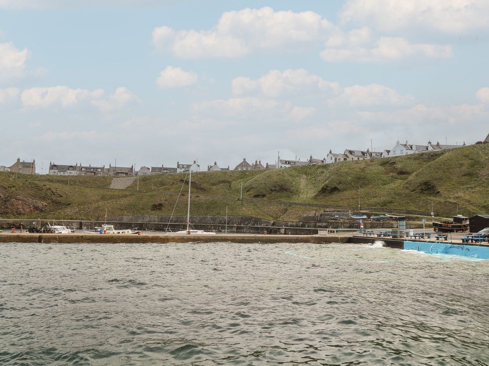 A view of houses on a hill by the water at Portknockie Cottage in Portknockie
