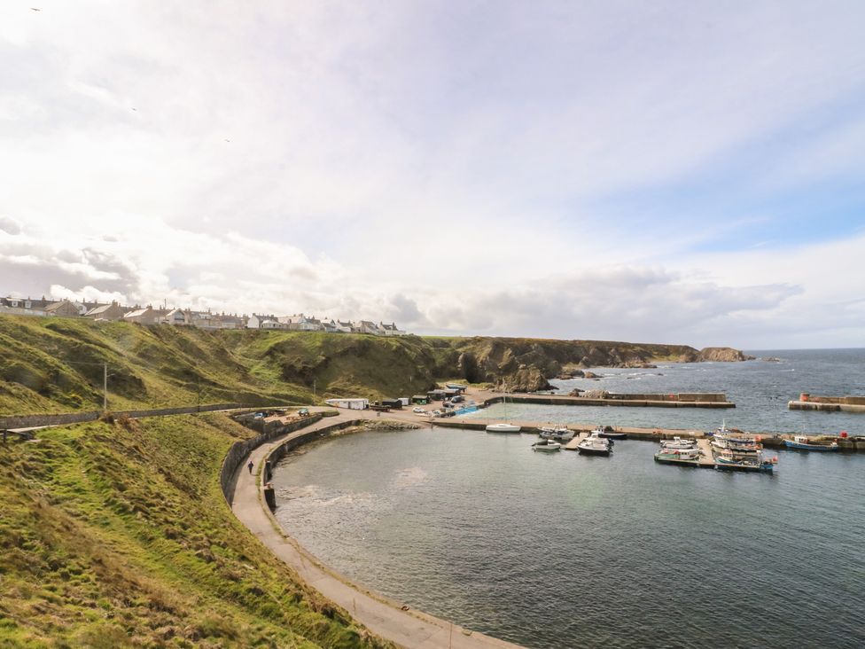 A harbor with boats and houses on the hills at Portknockie Cottage in Portknockie