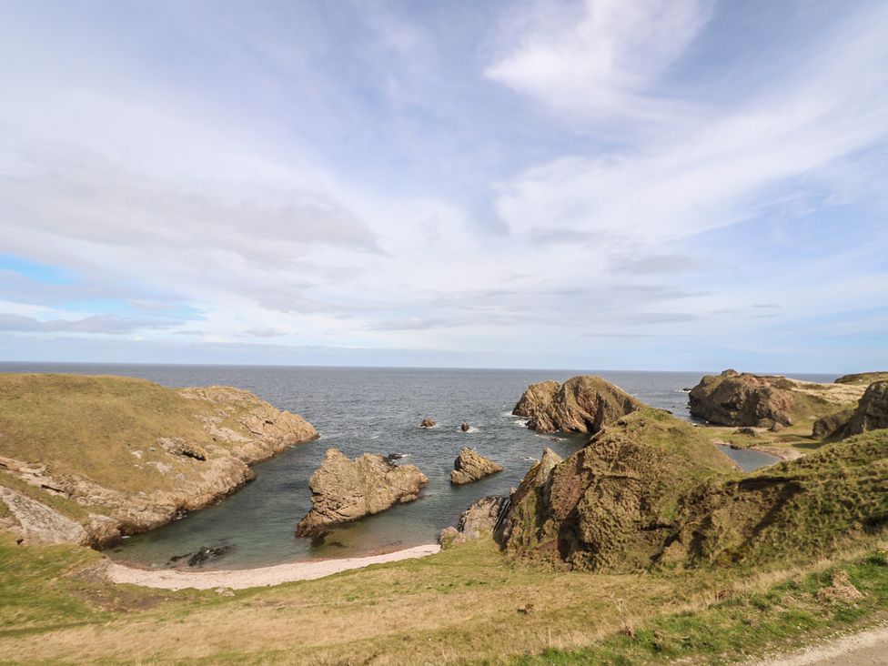 A coastal landscape with rock formations and ocean at Portknockie Cottage in Portknockie