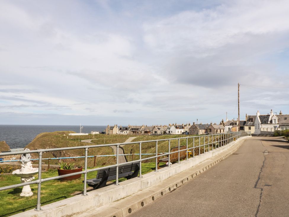 A coastal view with buildings and a path at Portknockie Cottage in Portknockie