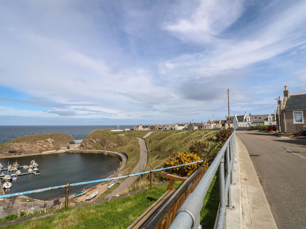 A harbor with boats and houses along the coast at Portknockie Cottage in Portknockie