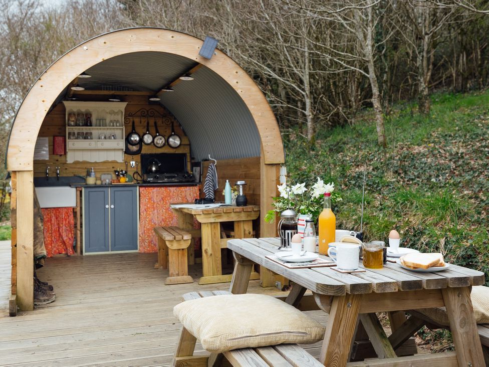 An outdoor kitchen setup with seating and dining items at Goldfinch in Launceston
