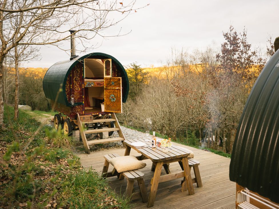 A caravan with a wooden table and chairs outside at Goldfinch in Launceston